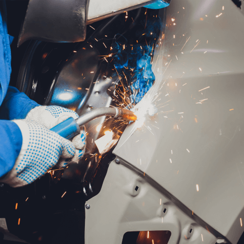 Mechanic welding damaged body on car